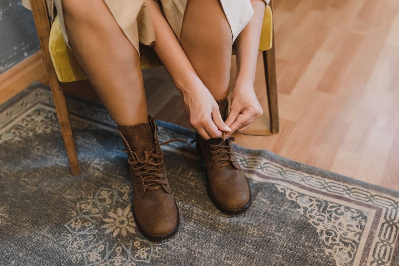 A person pulling on a leather western boot
